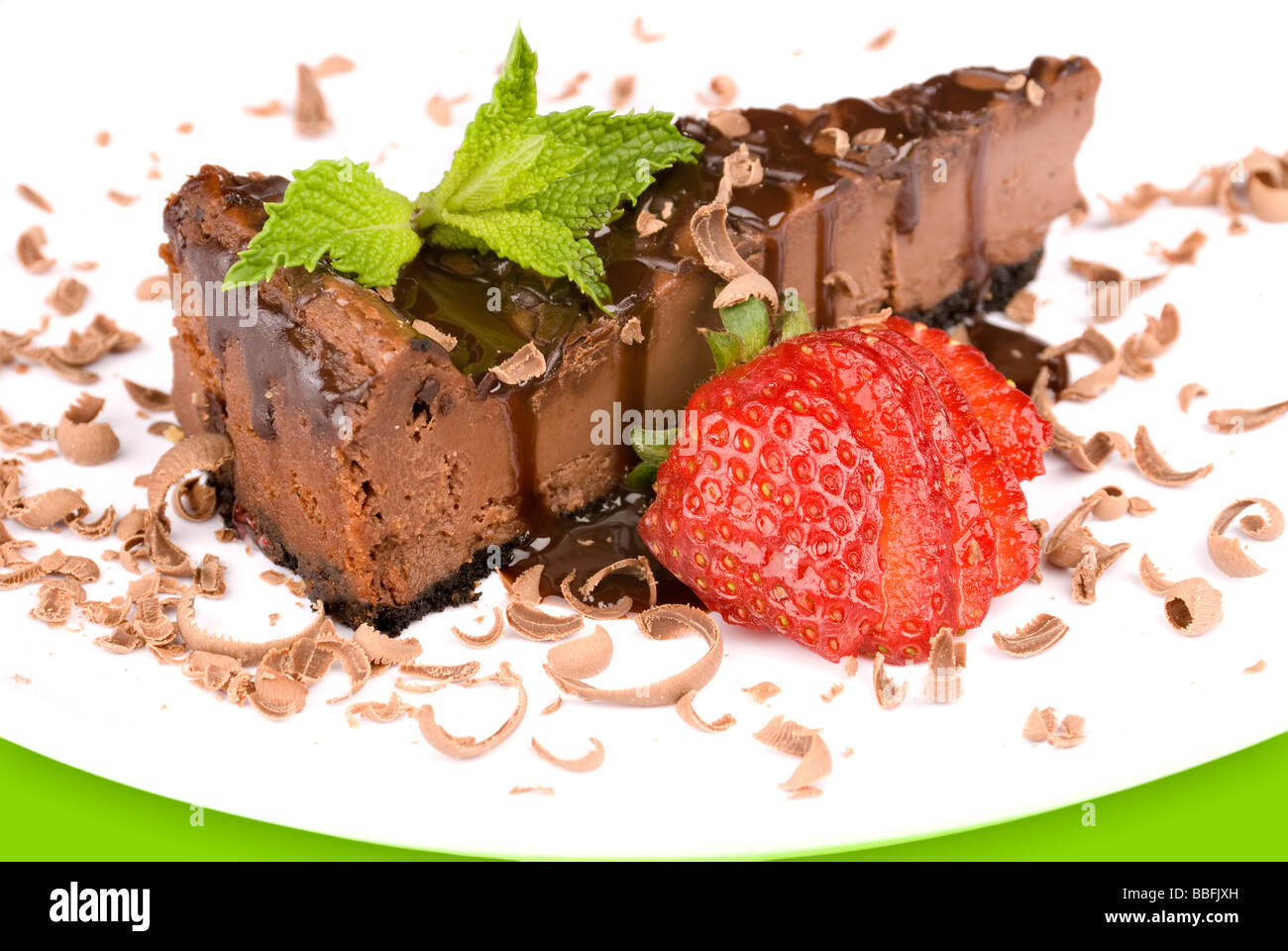 Eine Nahaufnahme ein Stück Schokolade Käsekuchen mit einer frischen Erdbeere garnieren und Minze Stockfoto