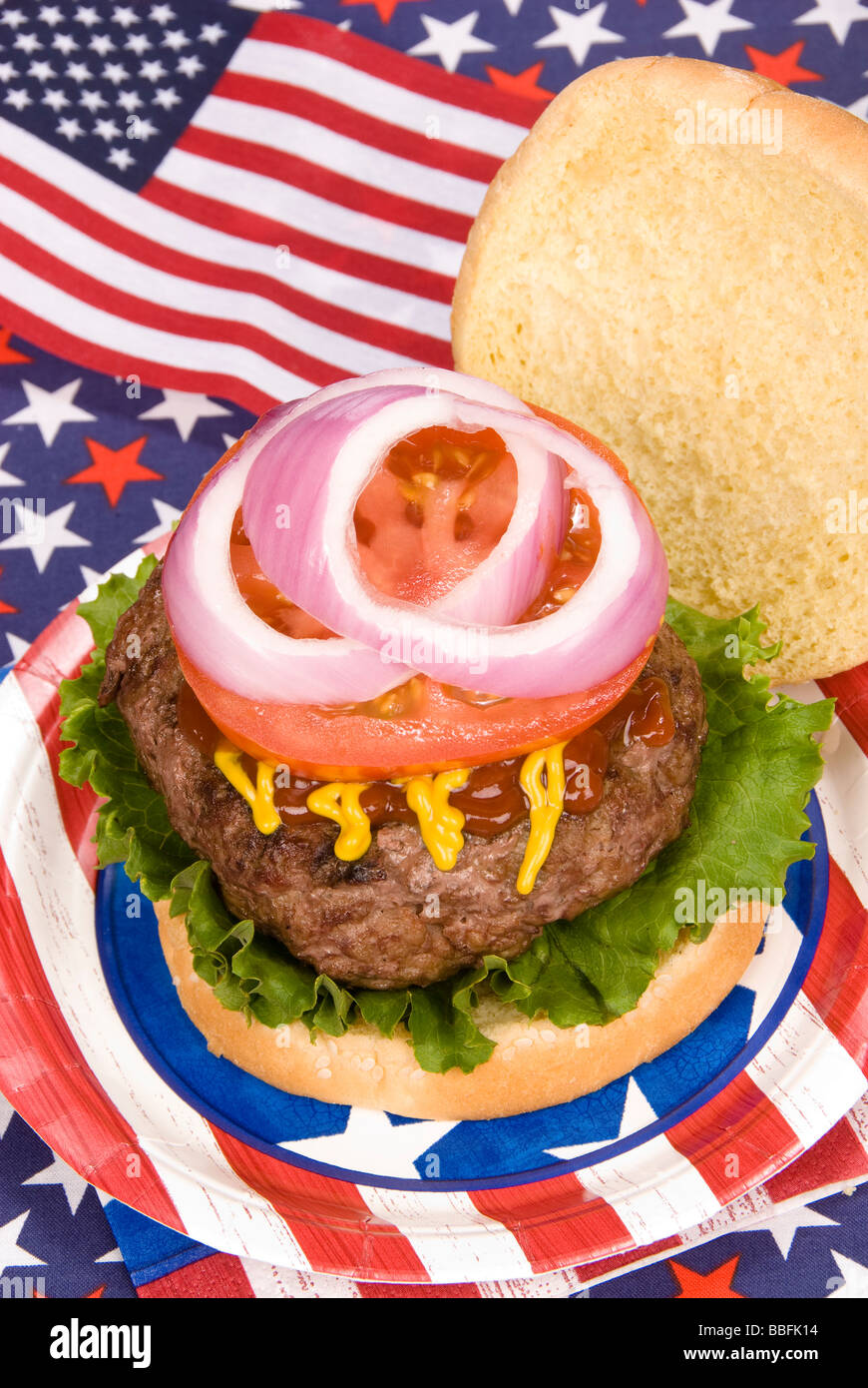 Eine saftige Hamburger mit Tomoato Zwiebel Senf und Ketchup mit einem vierten Juli patriotischen Thema Stockfoto