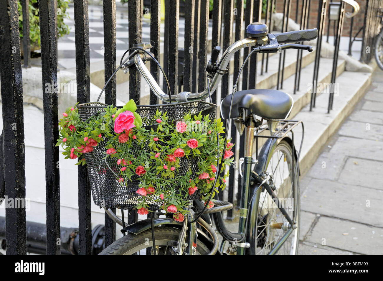Damenrad an Geländer gekettet und dekoriert mit Blumen Queen Square London England UK Stockfoto