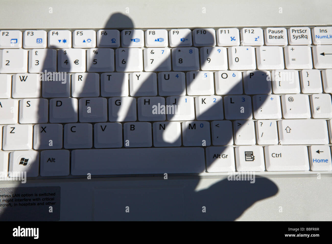 Schatten der Hand über die Computertastatur. Stockfoto