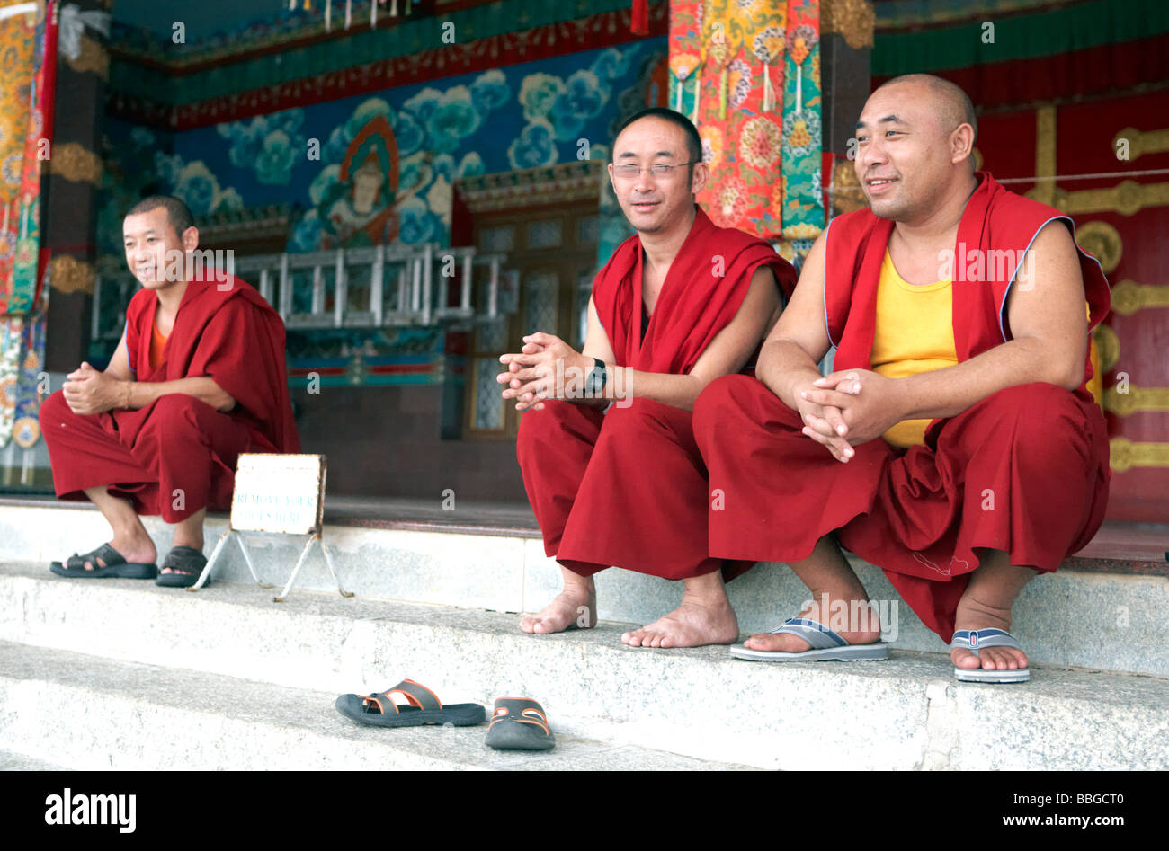 Buddhistische Mönche ausserhalb Kloster Sera Bylakuppe Koorg Karnataka Indien Sitzen Stockfoto