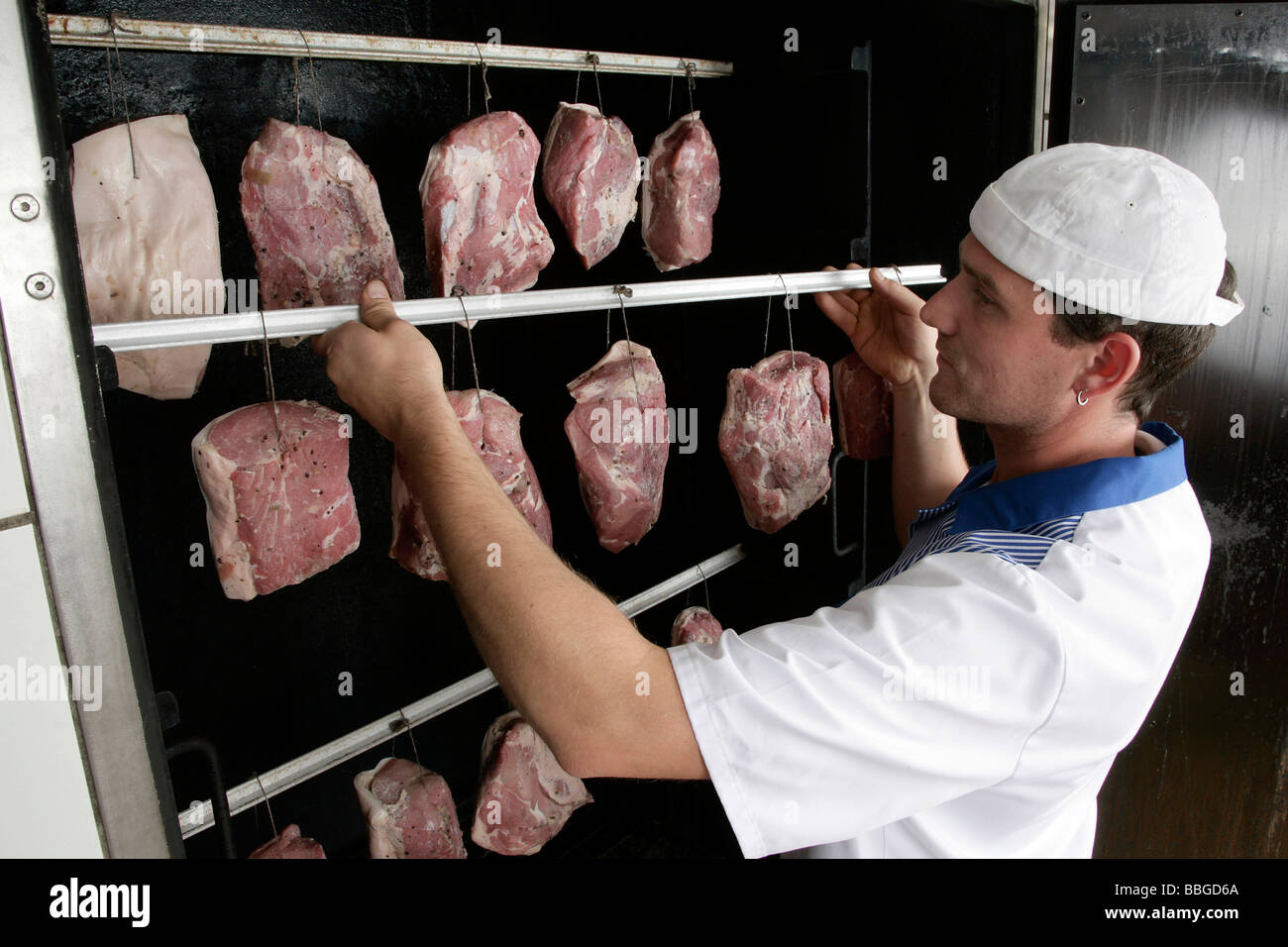 Metzger Gerhard Mader ist Schweinefleisch Gelenke in ein Raucher, Produktion der Bayerischen Spezialität Schwarzgeraeuchertes, geräucherte h hängen. Stockfoto