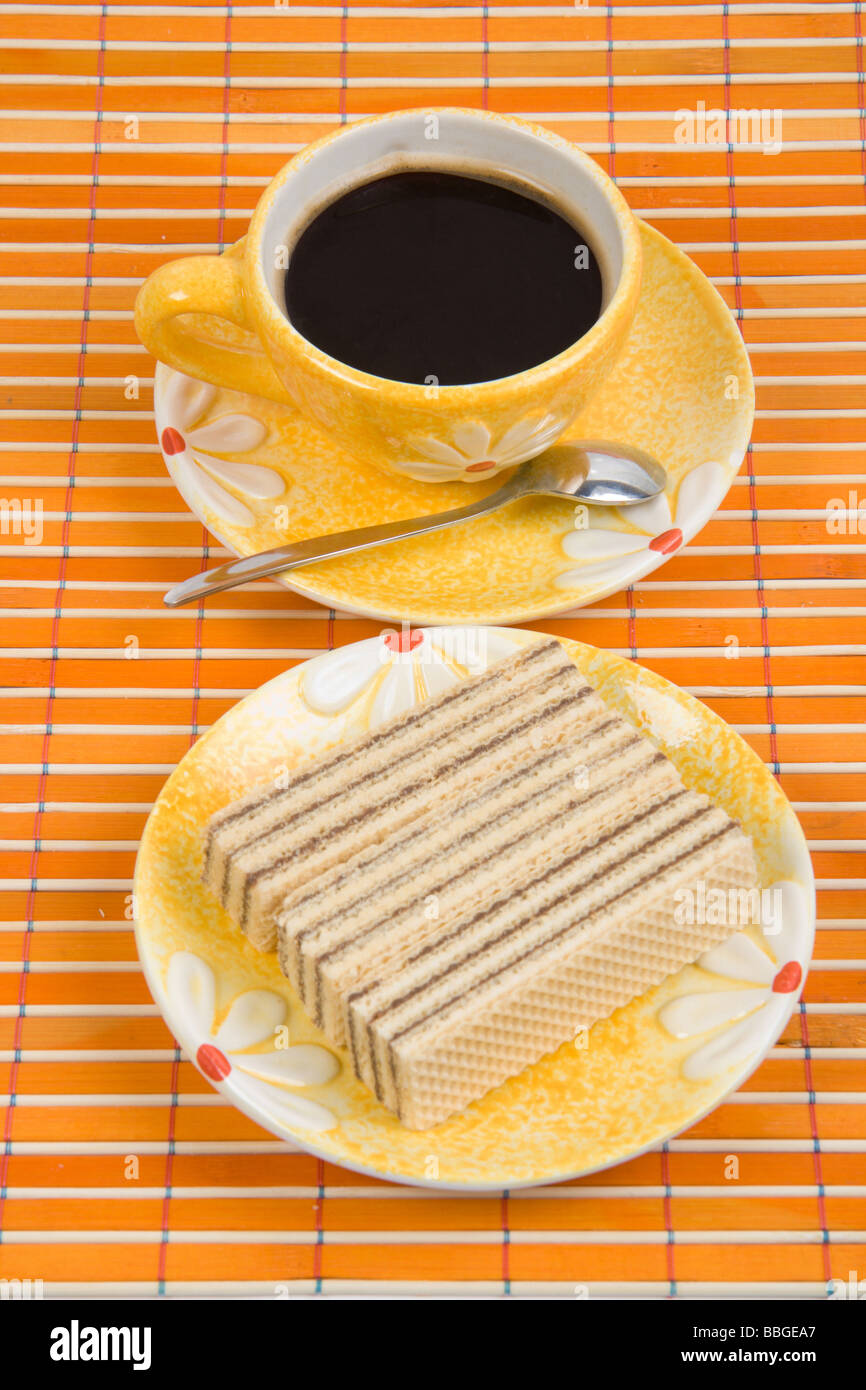 Waffel-Stück und Tasse mit Kaffee auf Bambus-Tischdecke hautnah Stockfoto