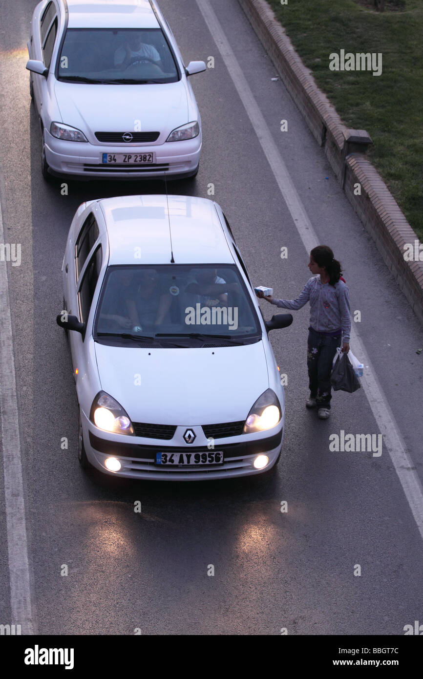 Istanbul Türkei Kind Bettler Pakete von Geweben unter den Verkehr auf einer belebten Straße zu verkaufen Stockfoto