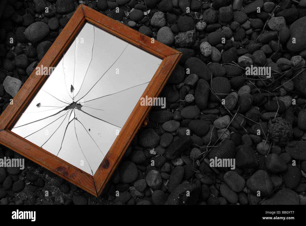 Zerbrochener Spiegel am steinigen Strand in selektiven Farbkorrektur Stockfoto