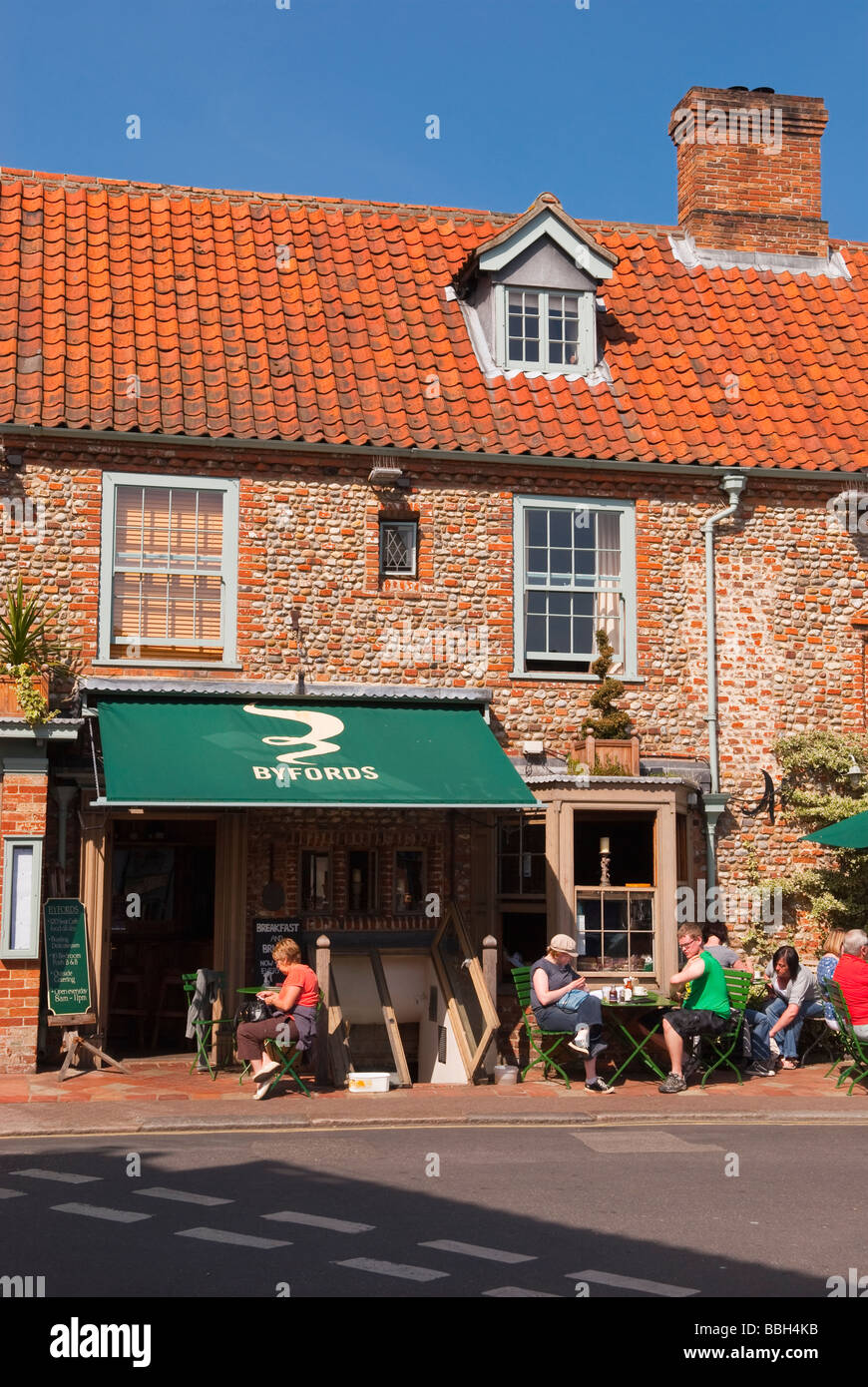 Kunden, die draußen in der Sonne trinken Tee und Kaffee im Café Byfords Feinkost Restaurant in Holt Norfolk Uk Stockfoto