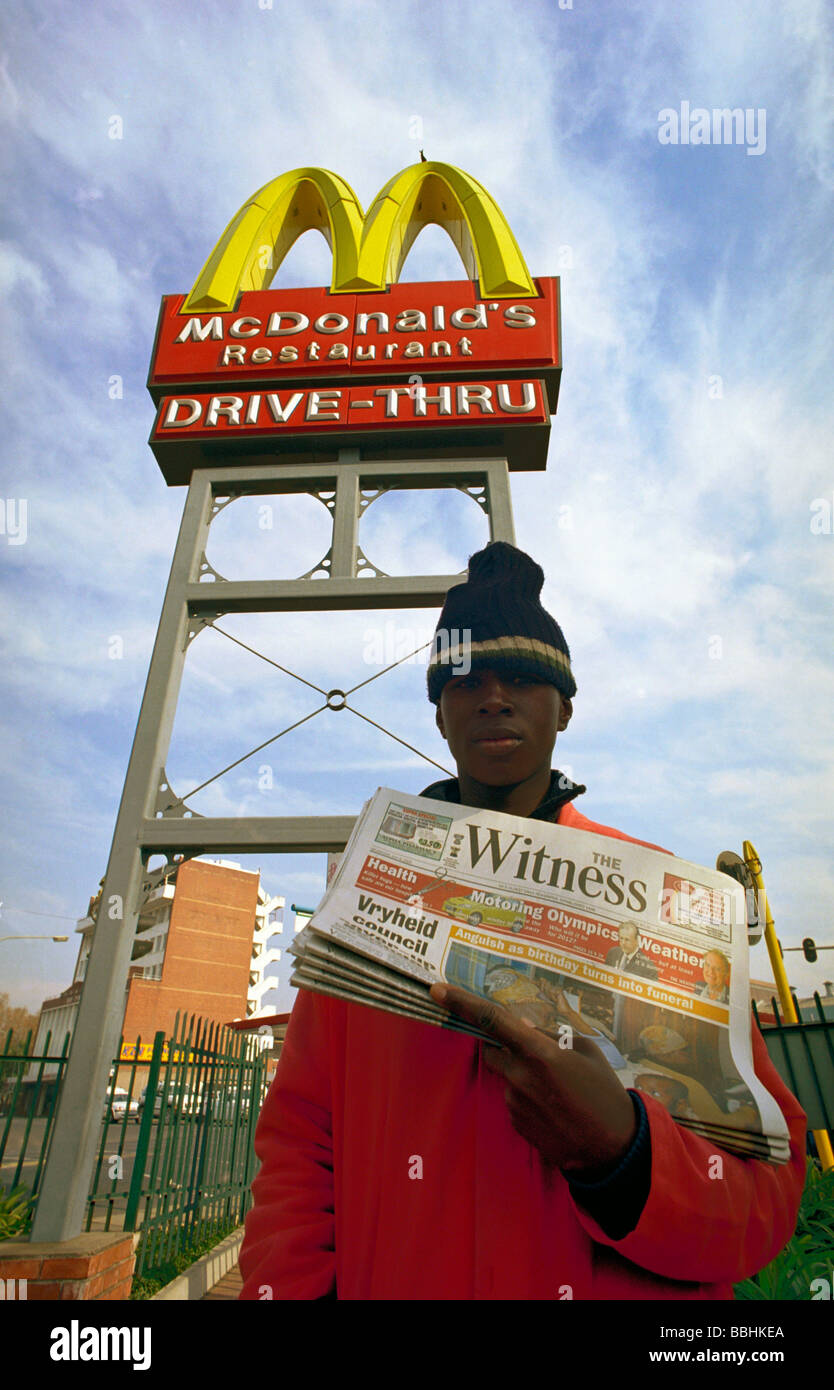 Deon Ncube verkauft der Zeuge Zeitung vor McDonald s goldene Bögen, das, die er verdient R30 täglich von 06:00 bis 11:00 er arbeitete Stockfoto