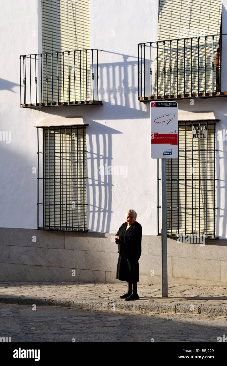 Ältere Spanierin an Bushaltestelle in schwarz gekleidet. Stockfoto
