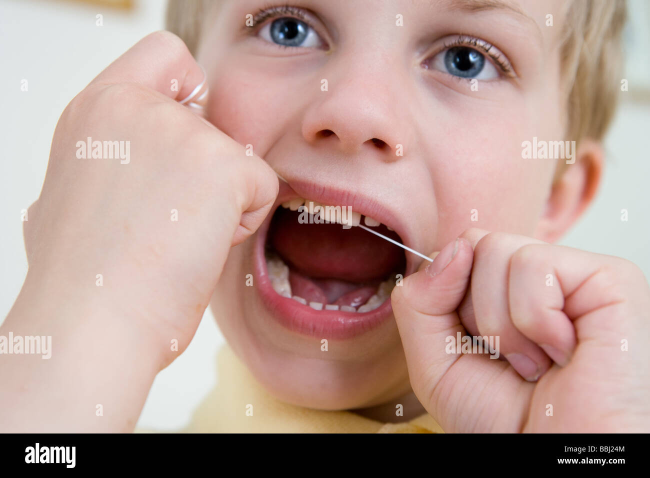 Ein kleiner Junge mit Zahnseide zur Pflege von Zähnen und Zahnfleisch Stockfoto