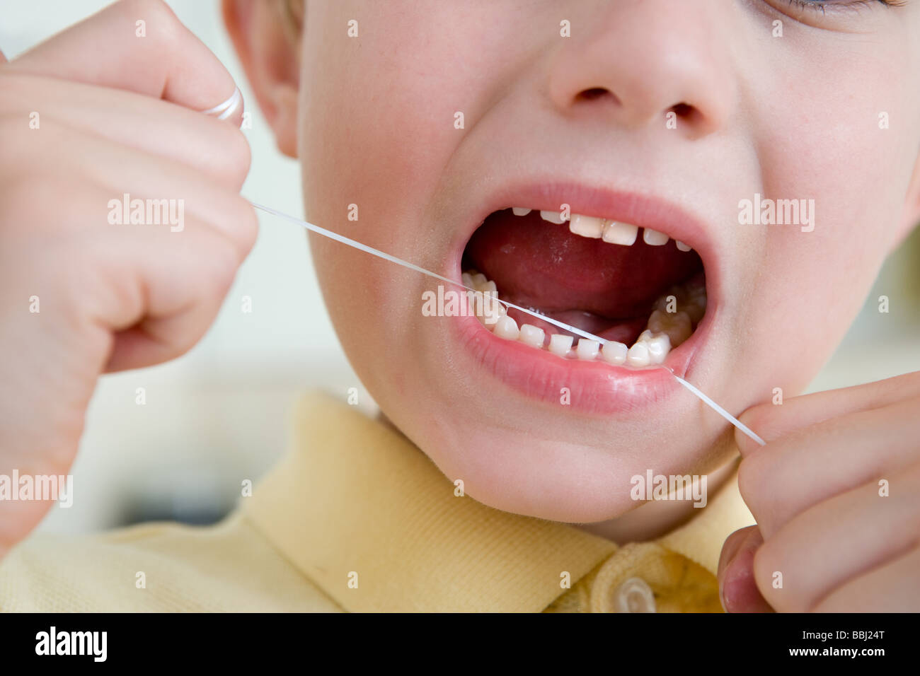 Ein kleiner Junge mit Zahnseide zur Pflege von Zähnen und Zahnfleisch Stockfoto