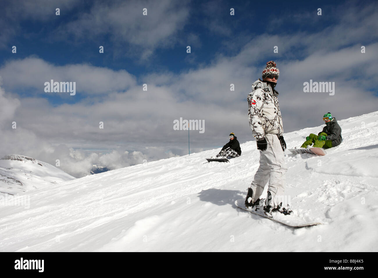 Snowboarder sitzen warten Freunde abseits der Pisten im Skigebiet Les Deux Alpen, Teil der Grande Galaxie Skigebiet, Frankreich Stockfoto