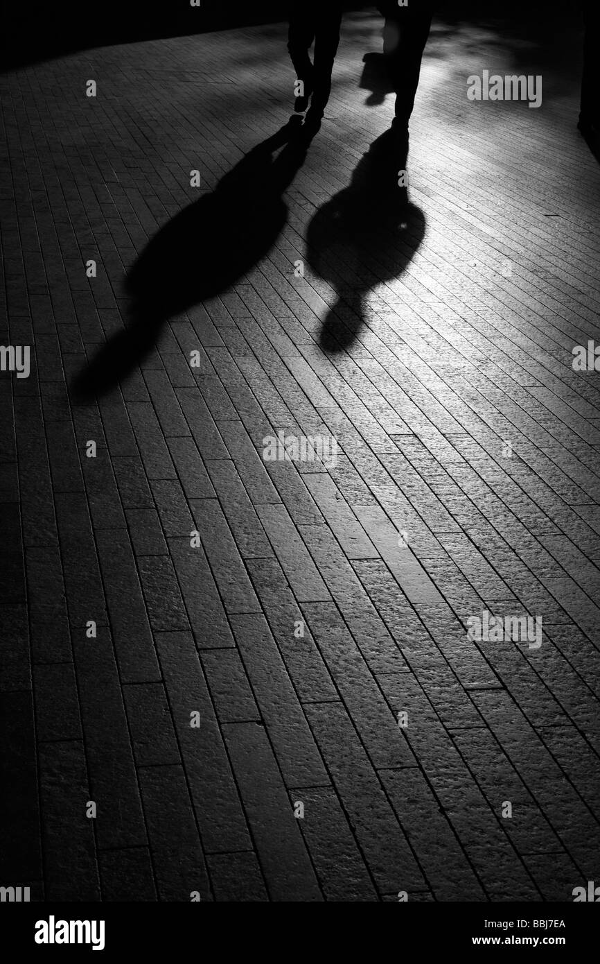 Silhouetten und Schatten der Fußgänger zu Fuß in den späten Abend Sonnenschein entlang der Thames Path, City of London, UK Stockfoto