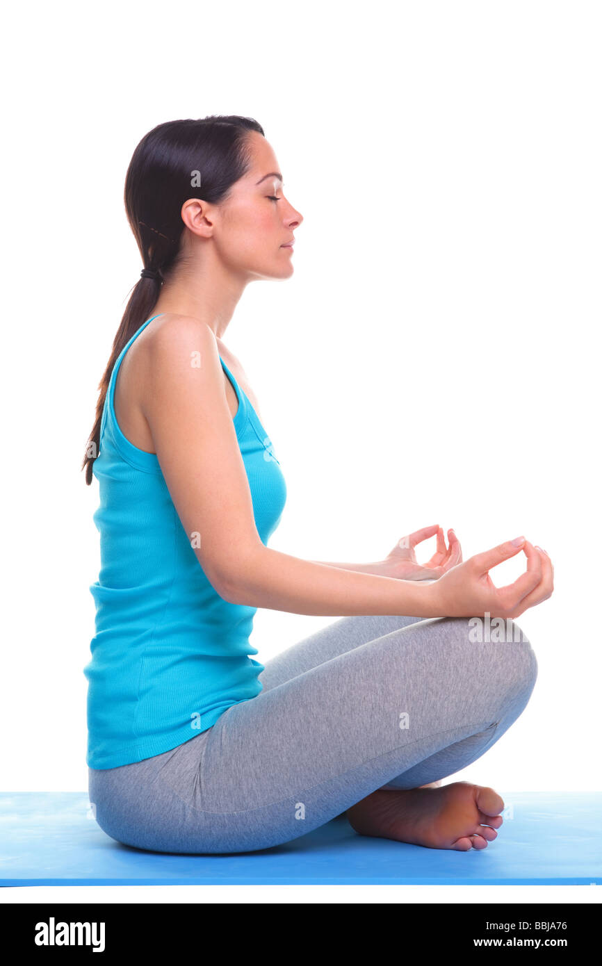 Brünette Frau Seitenansicht saß auf einer Yogamatte im Lotussitz isoliert auf weißem Hintergrund Stockfoto
