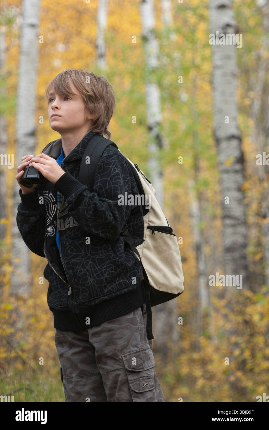 Zehn Jahre alter Junge mit Fernglas tragen Hanf Rucksack, See Katherine Riding Mountain National Park, Manitoba Stockfoto