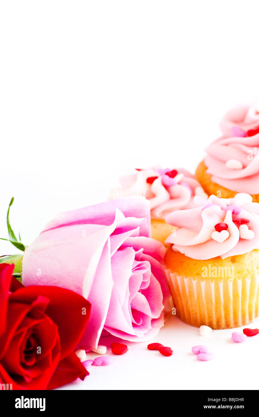 Valentinstag-Rosen und kleine Kuchen mit rosa Zuckerguss Stockfoto