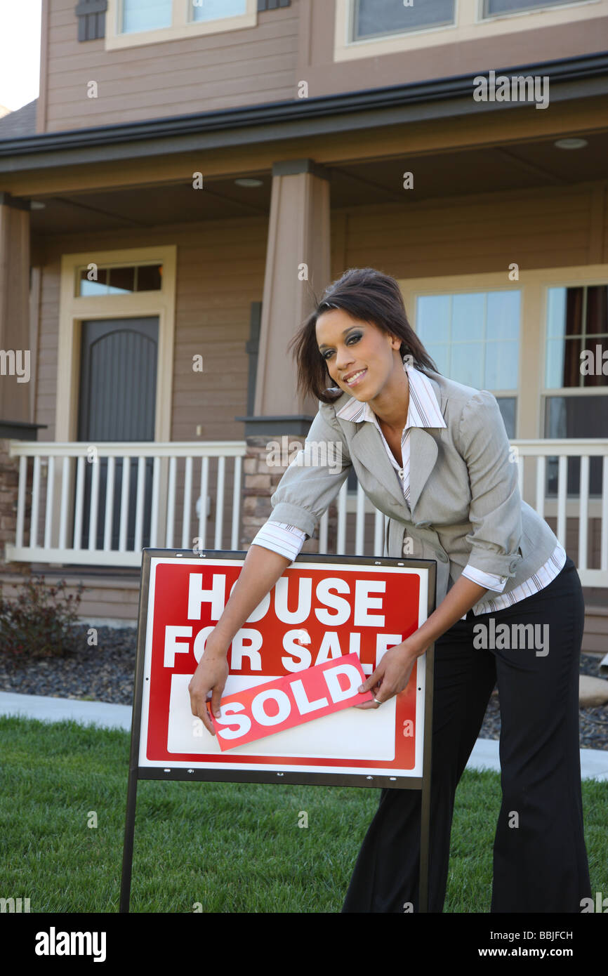 Immobilienmakler mit verkauften Schild vor Haus Stockfoto