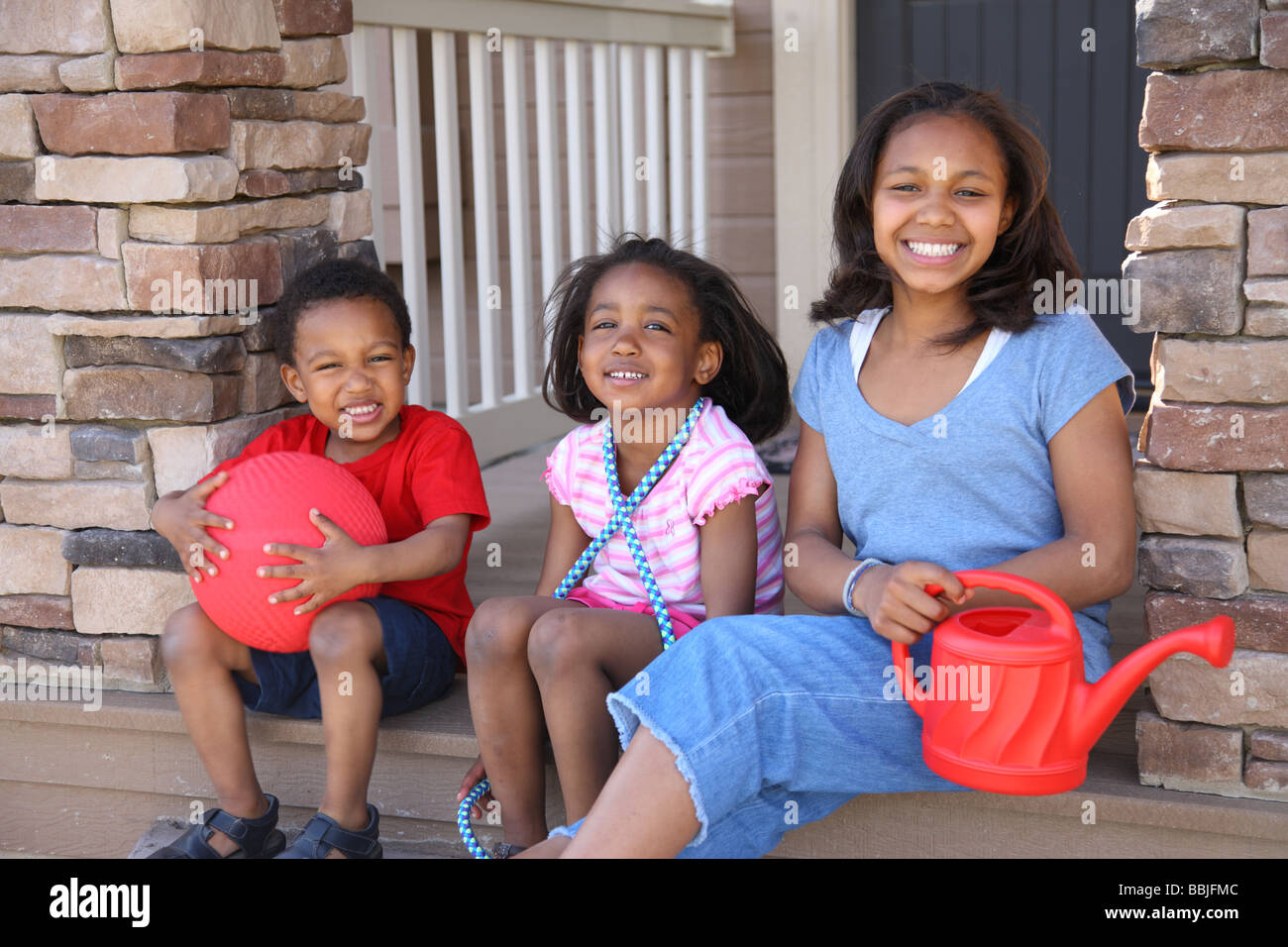 Drei Kinder mit Spielzeug auf Veranda Stockfoto
