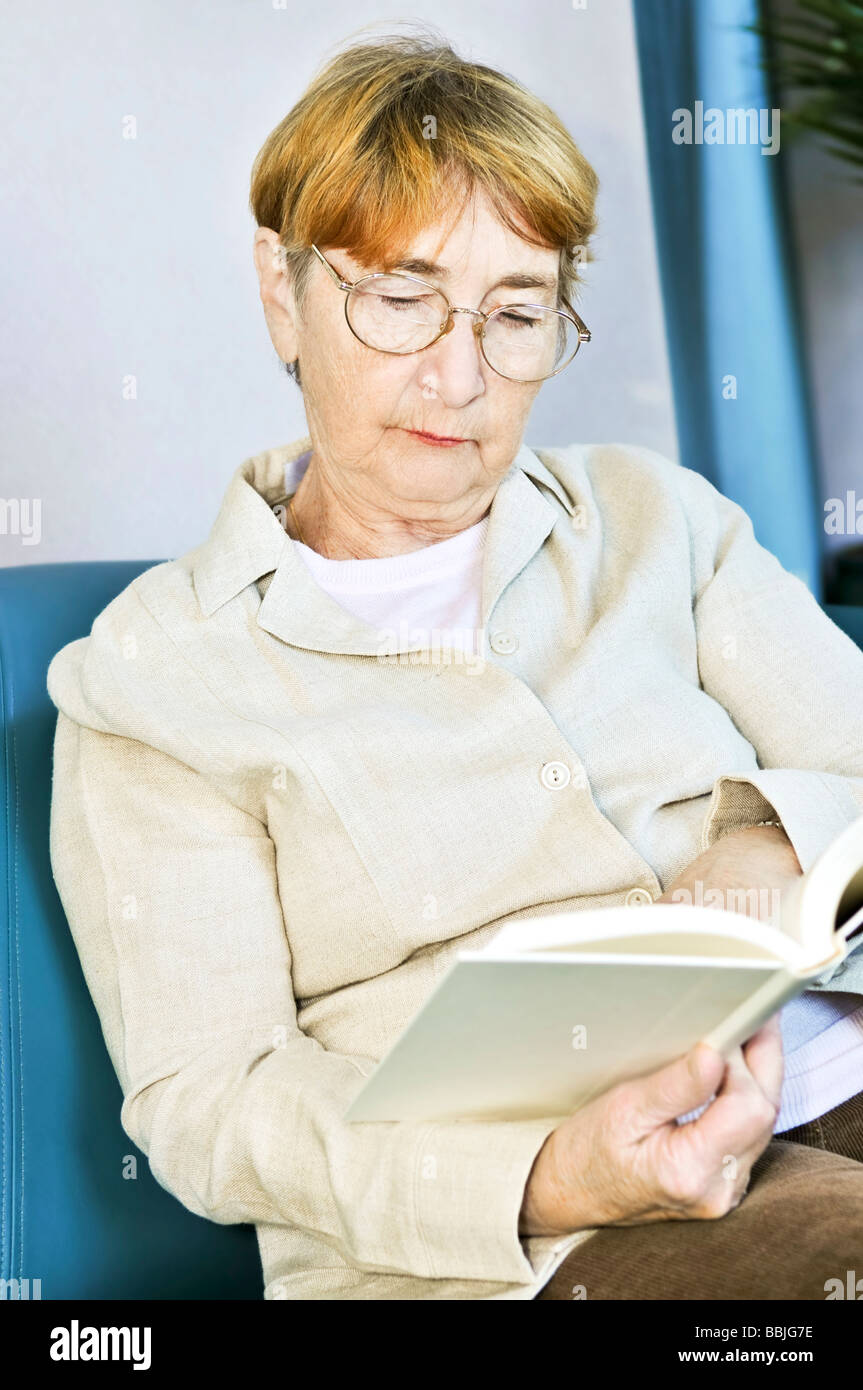 Ältere Frau entspannend auf Couch, ein Buch zu lesen Stockfoto