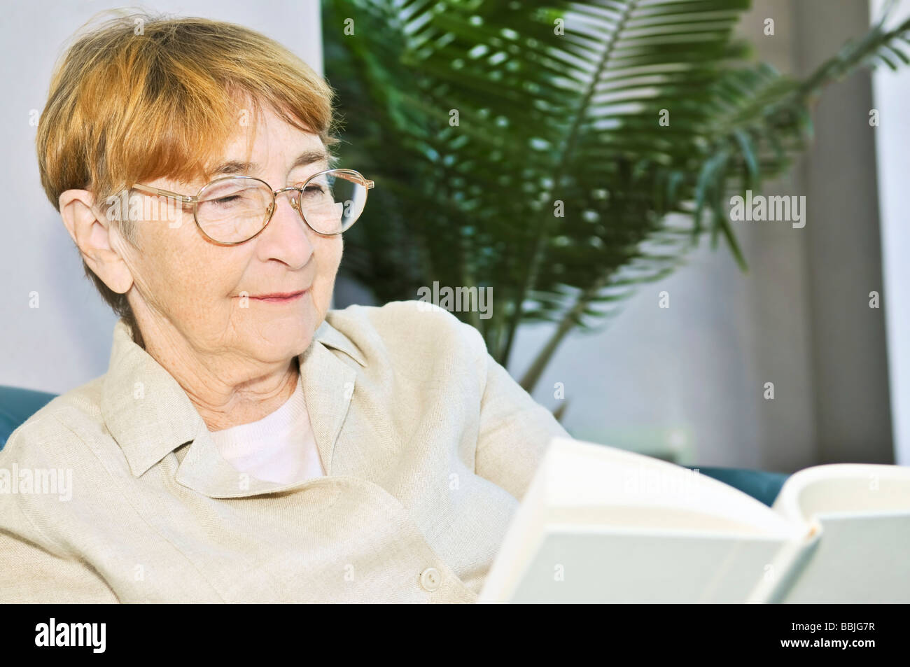 Ältere Frau entspannend auf Couch, ein Buch zu lesen Stockfoto
