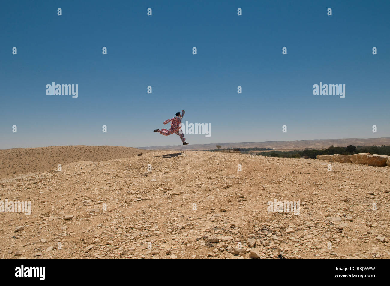 Junger Mann, gekleidet wie ein Clown springen in der Negev-Wüste Südisrael Stockfoto