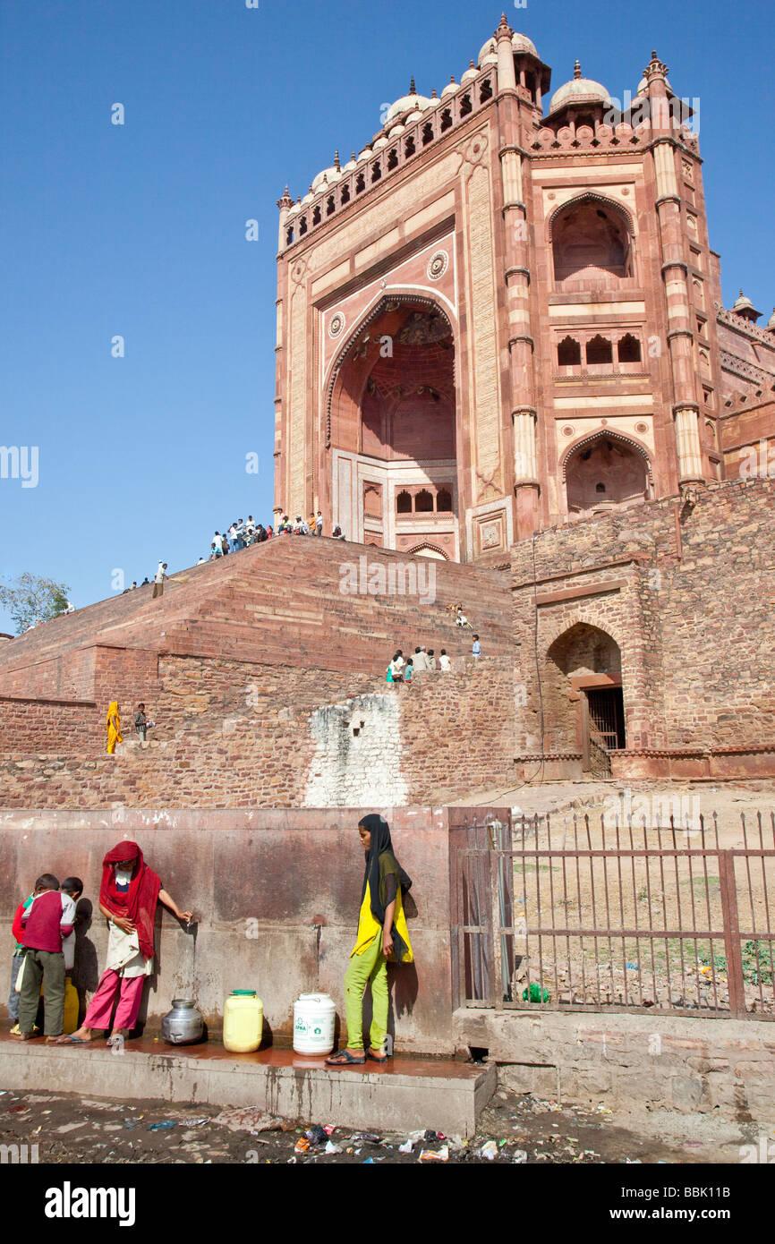 Mädchen füllen Wassereimer aus einer öffentlichen Quelle vor der Moschee in Fatehpur Sikri Indien Stockfoto