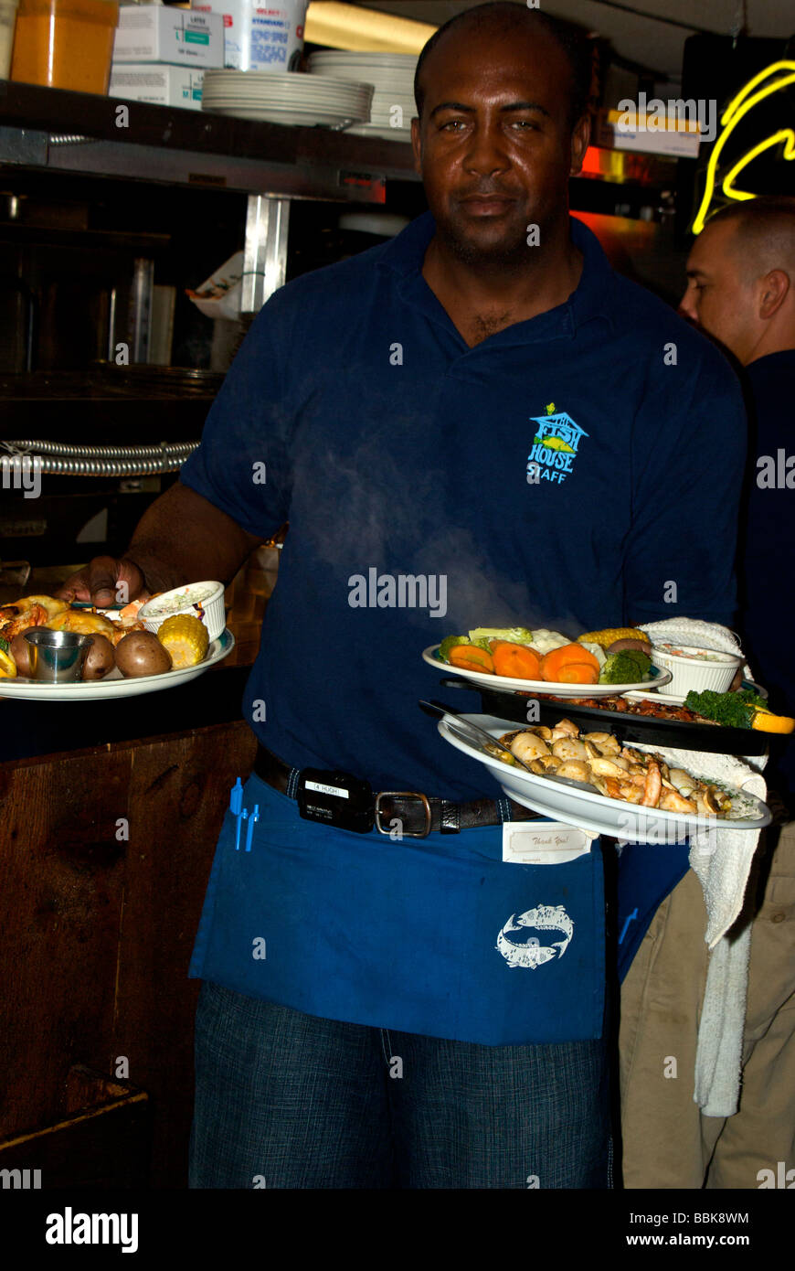 Erfahrener Kellner an das berühmte Fischrestaurant Haus in Key Largo einen Arm voll dampfend heiße Meeresfrüchte Vorspeisen servierfertig Stockfoto