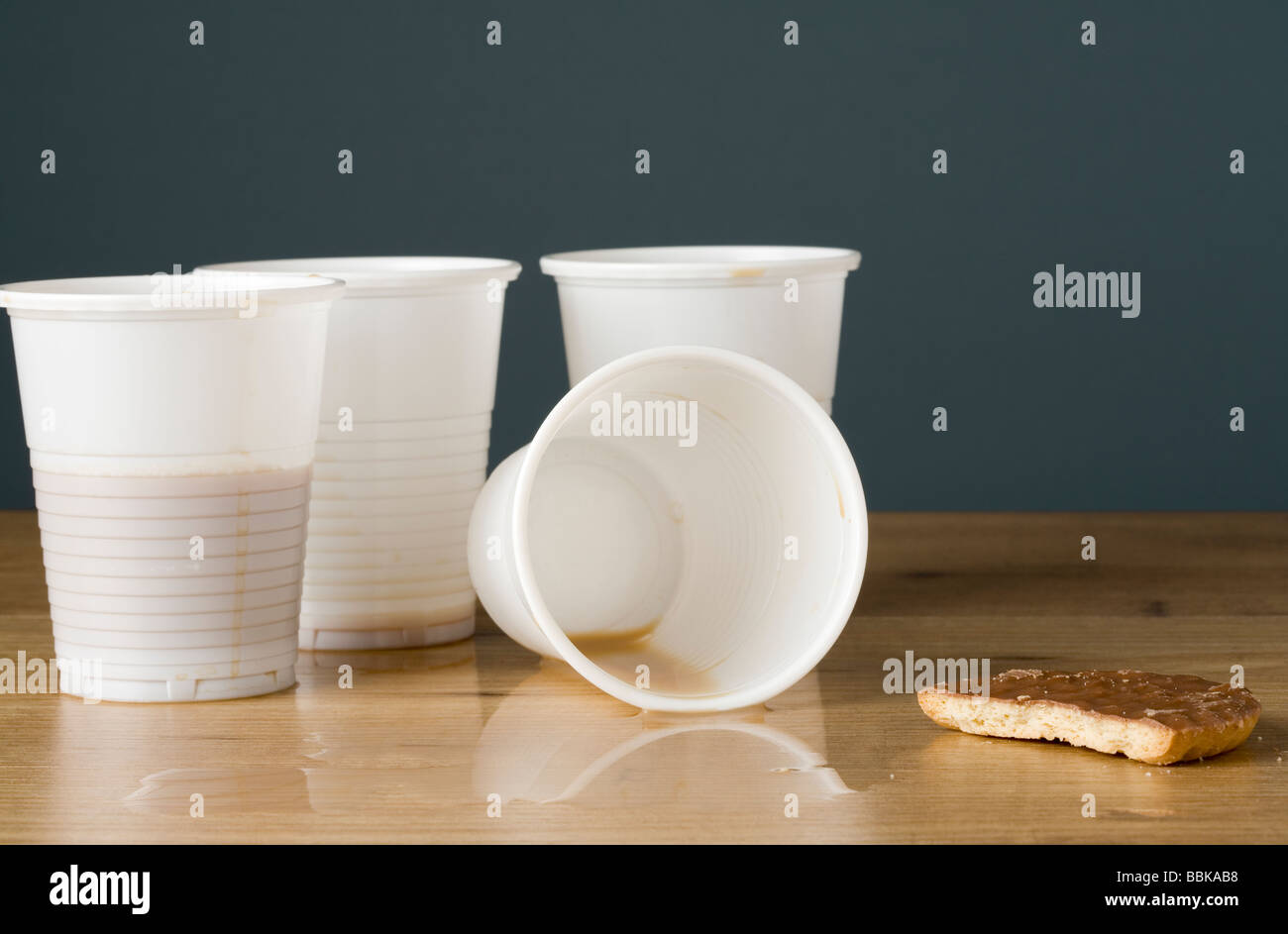 Kunststoff Kaffeetassen mit Bodensatz von Kaffee und eine Hälfte gegessen Keks Stockfoto