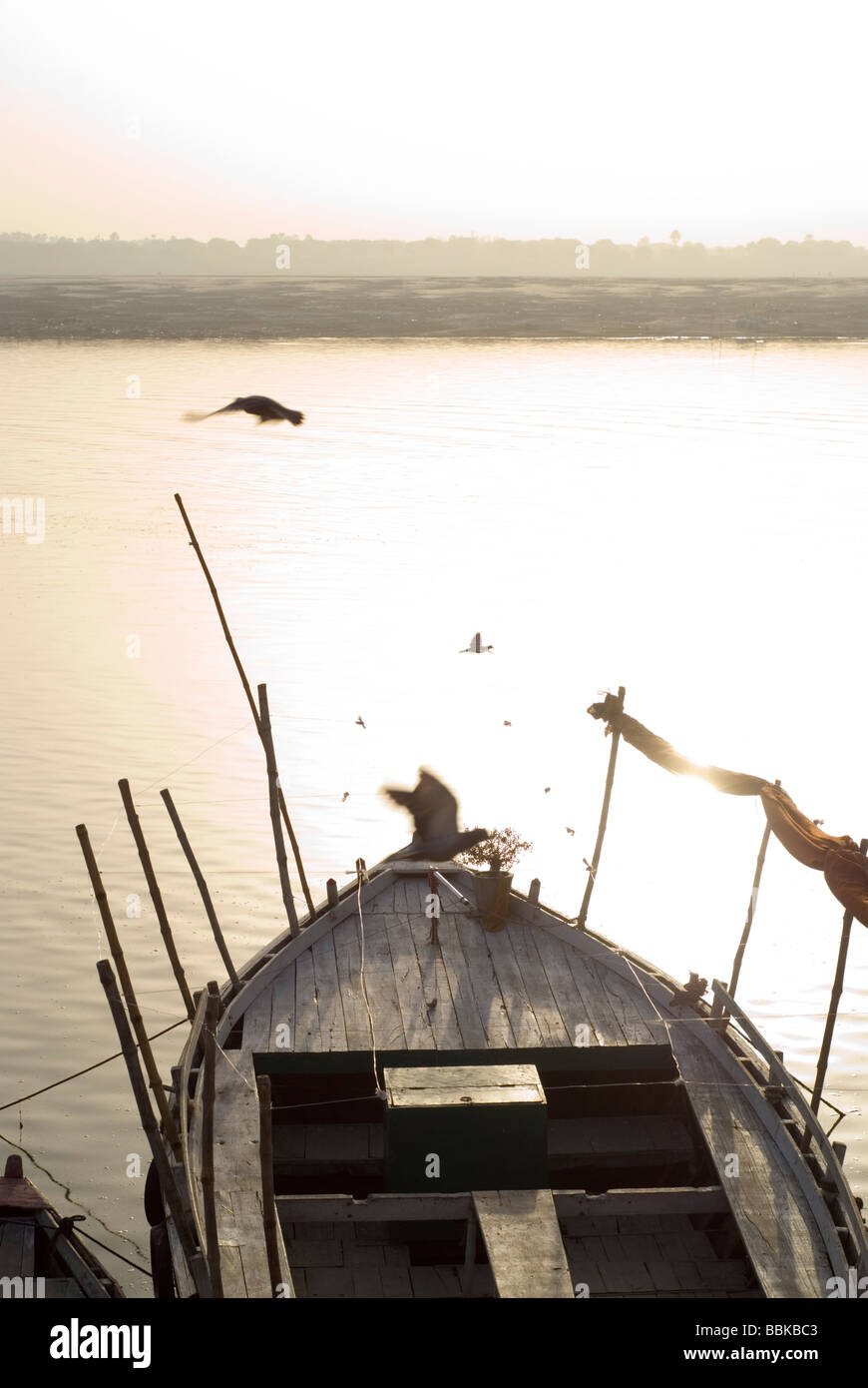 Sonnenaufgang über dem Ganges. Vögel fliegen über ein großes Boot auf Sonnenaufgang. Ganges River Bank, Varanasi, Indien. Stockfoto