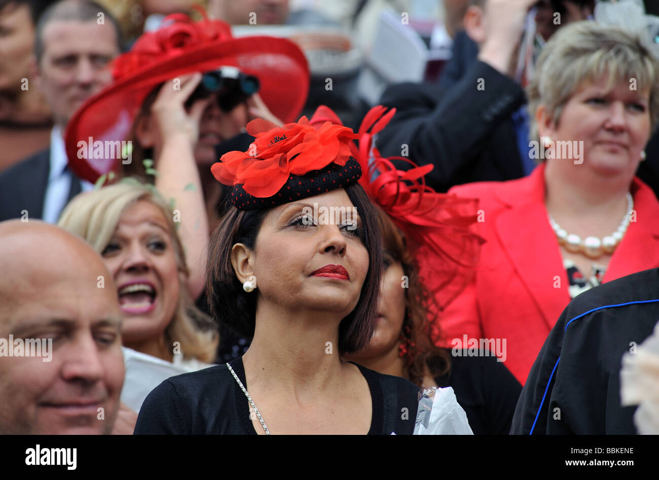 Eine Frau Rennen Goer in einem leuchtend roten Hut an der Epsom Derby nach einem Rennen Stockfoto