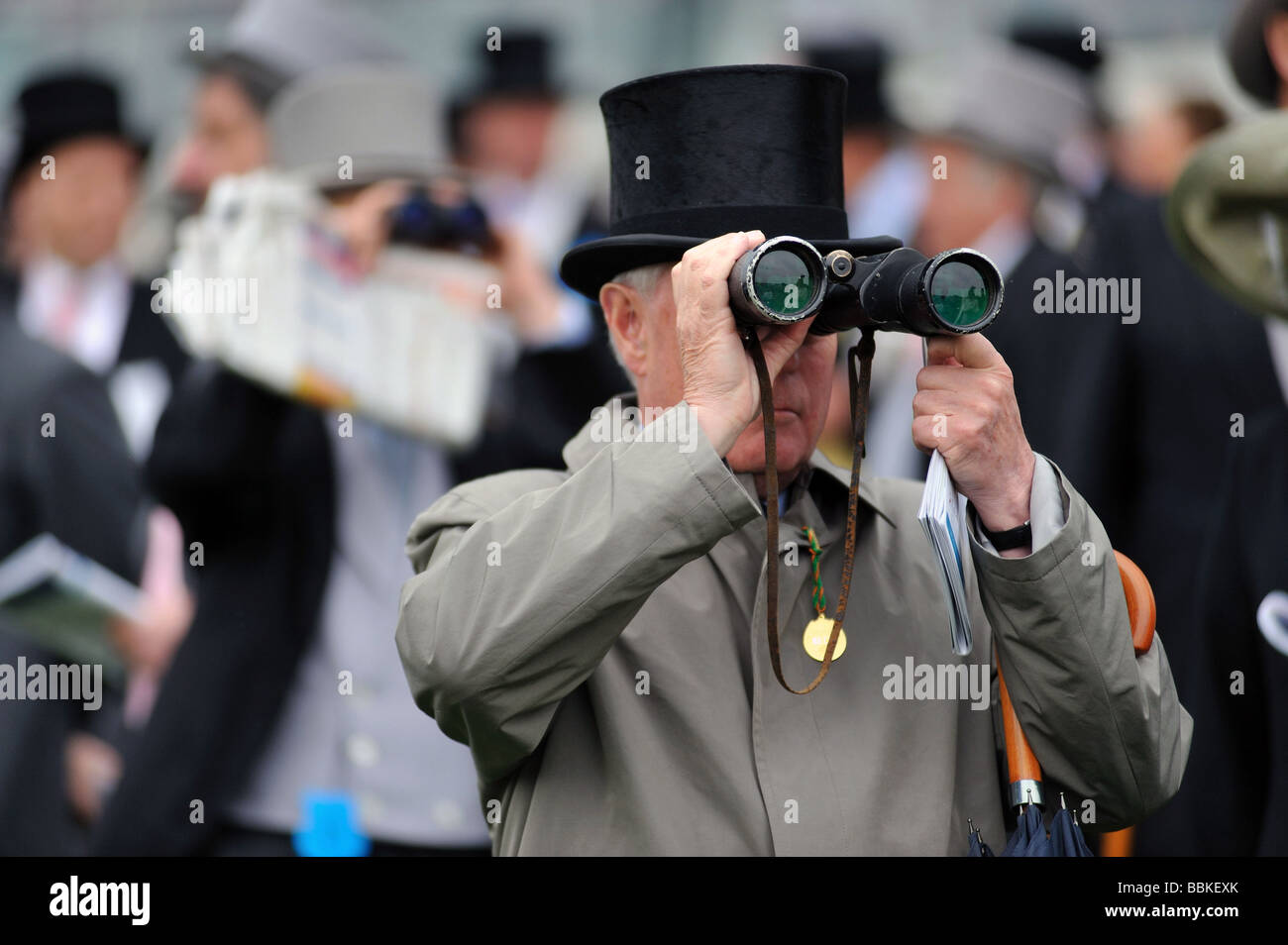 Ein Rennen Goer trägt einen Hut und formale Suiteat das Epsom Derby nach dem Rennen mit seinem Fernglas Stockfoto