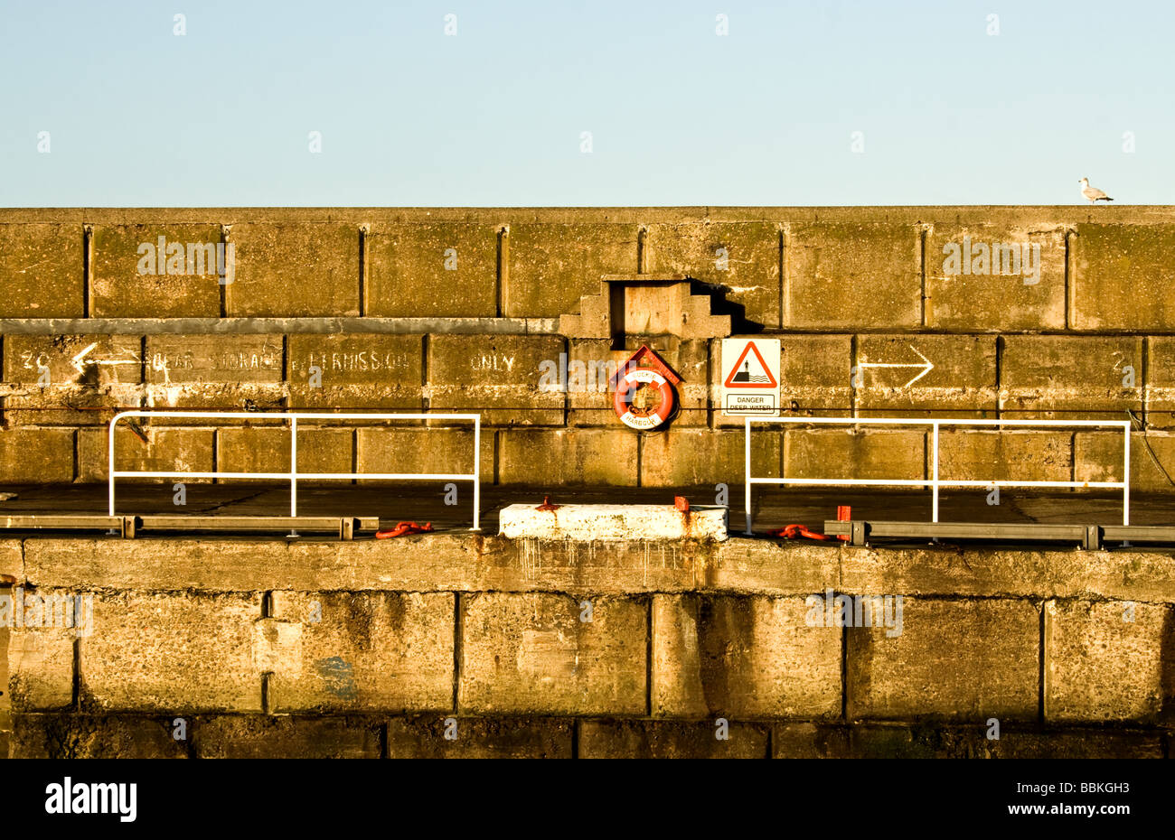 Rettungsring durch ein Wetter geschlagen Steinmauer hinter einer Metallschiene Stockfoto