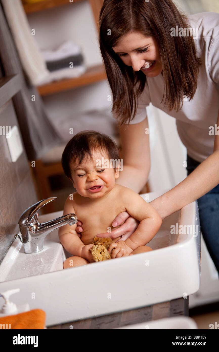 Neun Monate altes Baby Niesen während im Waschbecken gebadet wird Stockfoto