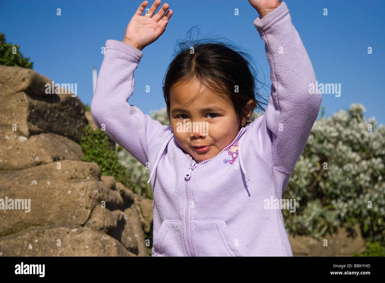 Ein halb-Thai-Mädchen springt von einer künstlichen Felswand entlang einer sonnigen Strandpromenade Skegness Stockfoto