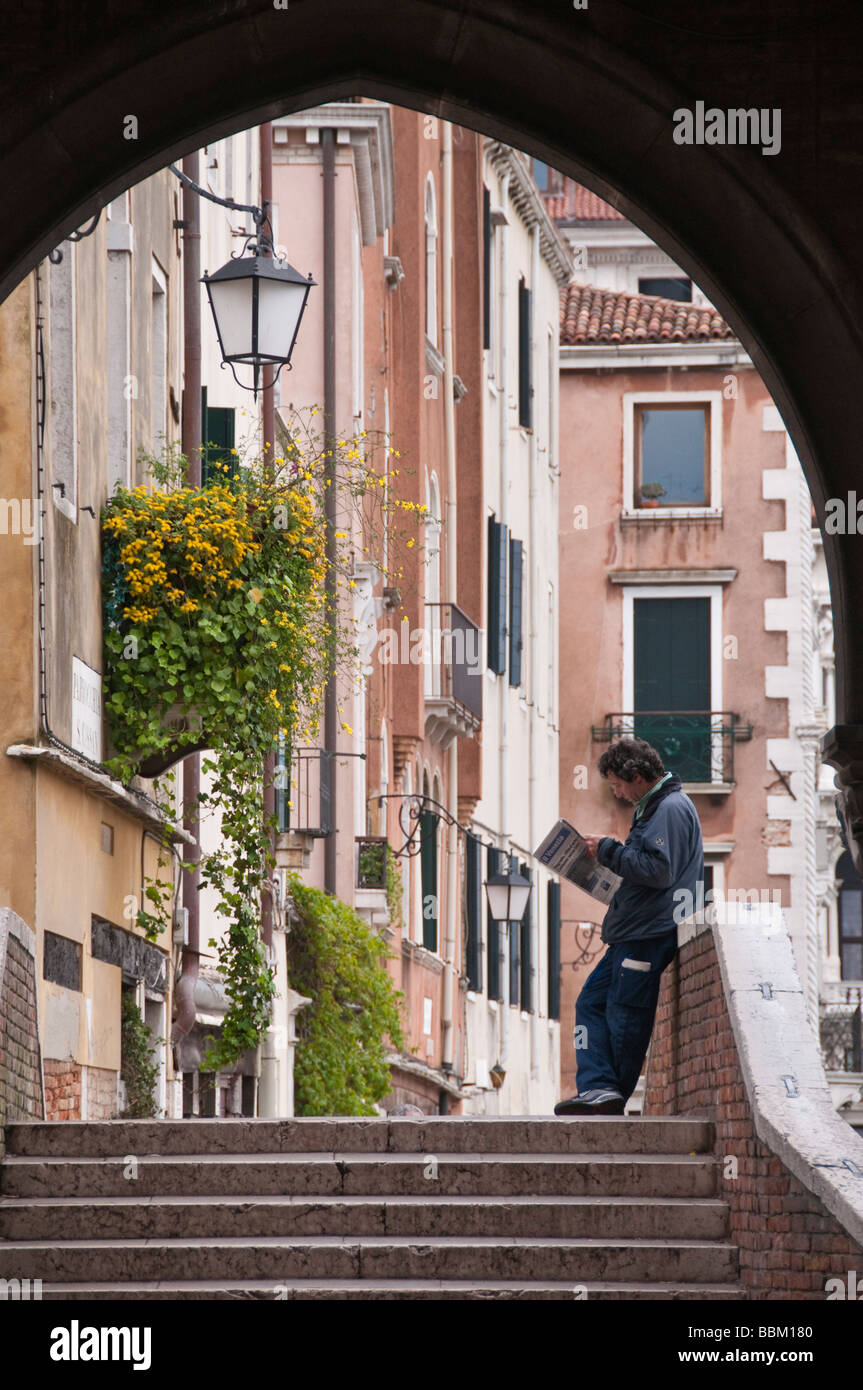 Mann liest Morgenzeitung auf Kanalbrücke San Polo in Venedig Italien Stockfoto