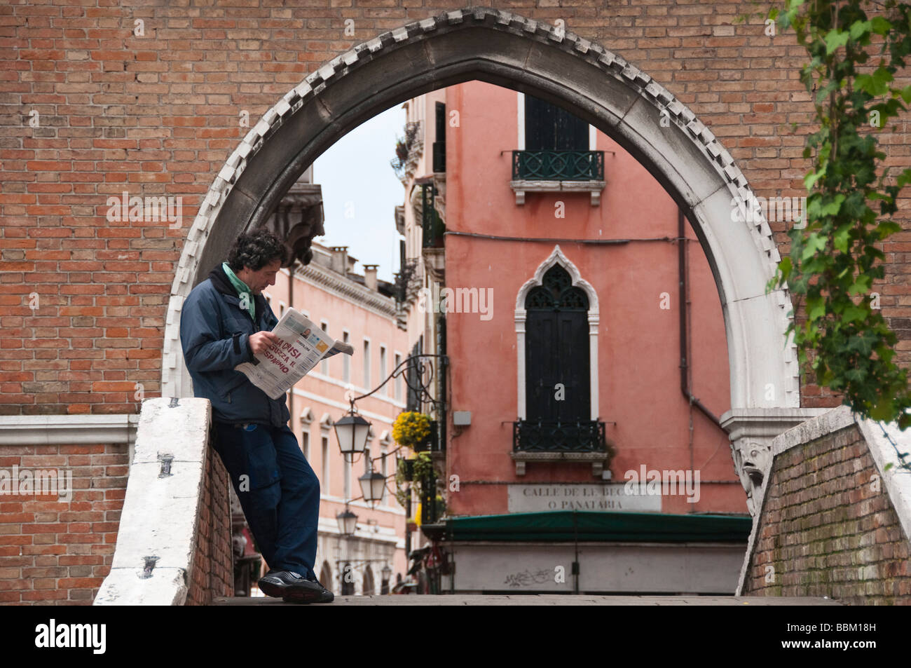 Mann liest Morgenzeitung auf Kanalbrücke San Polo in Venedig Italien Stockfoto