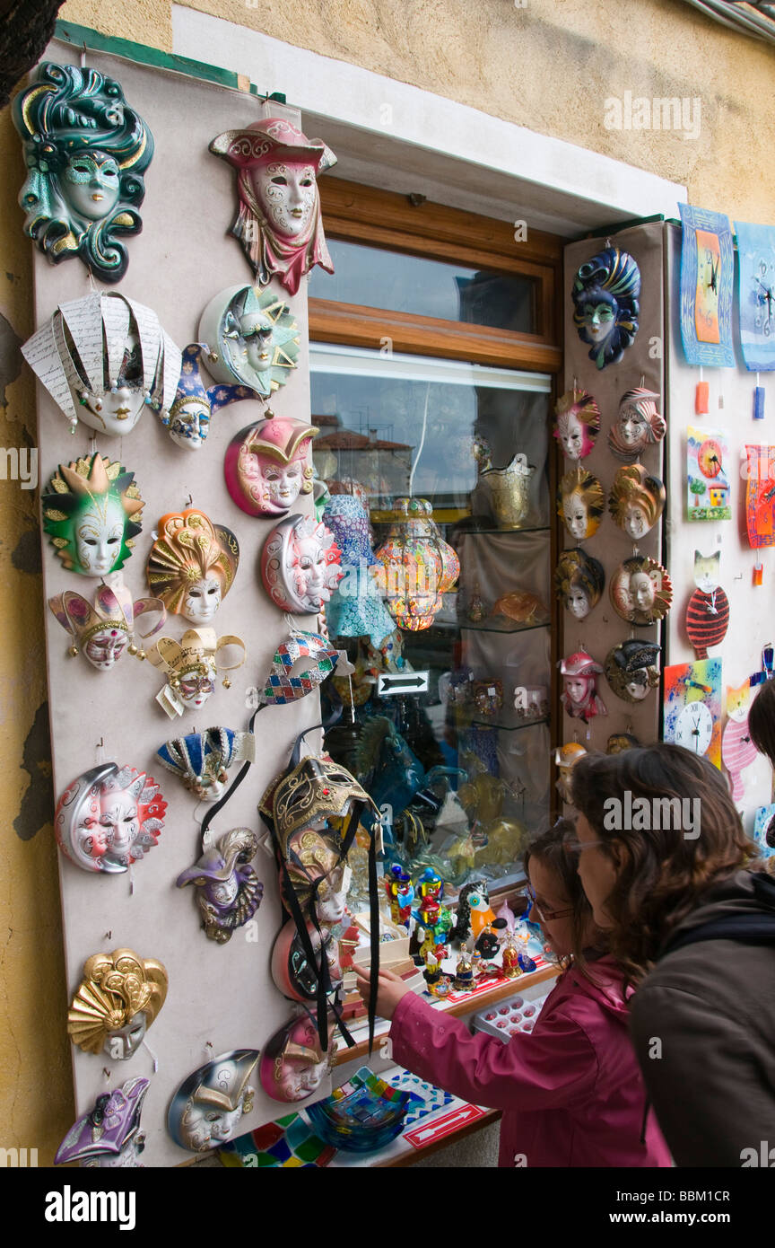 Touristen auf der Suche bei Gesichtsmasken außerhalb ein Souvenier shop Fenster Murano Venedig Italien Stockfoto