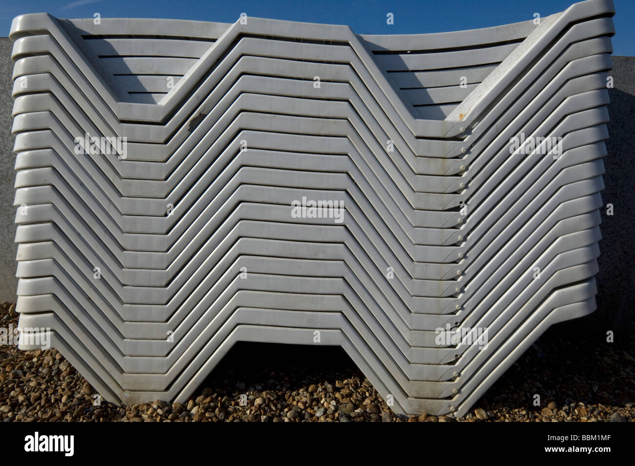 Ein Stapel der Plastikstühle auf einen englischen Kieselstrand Stockfoto