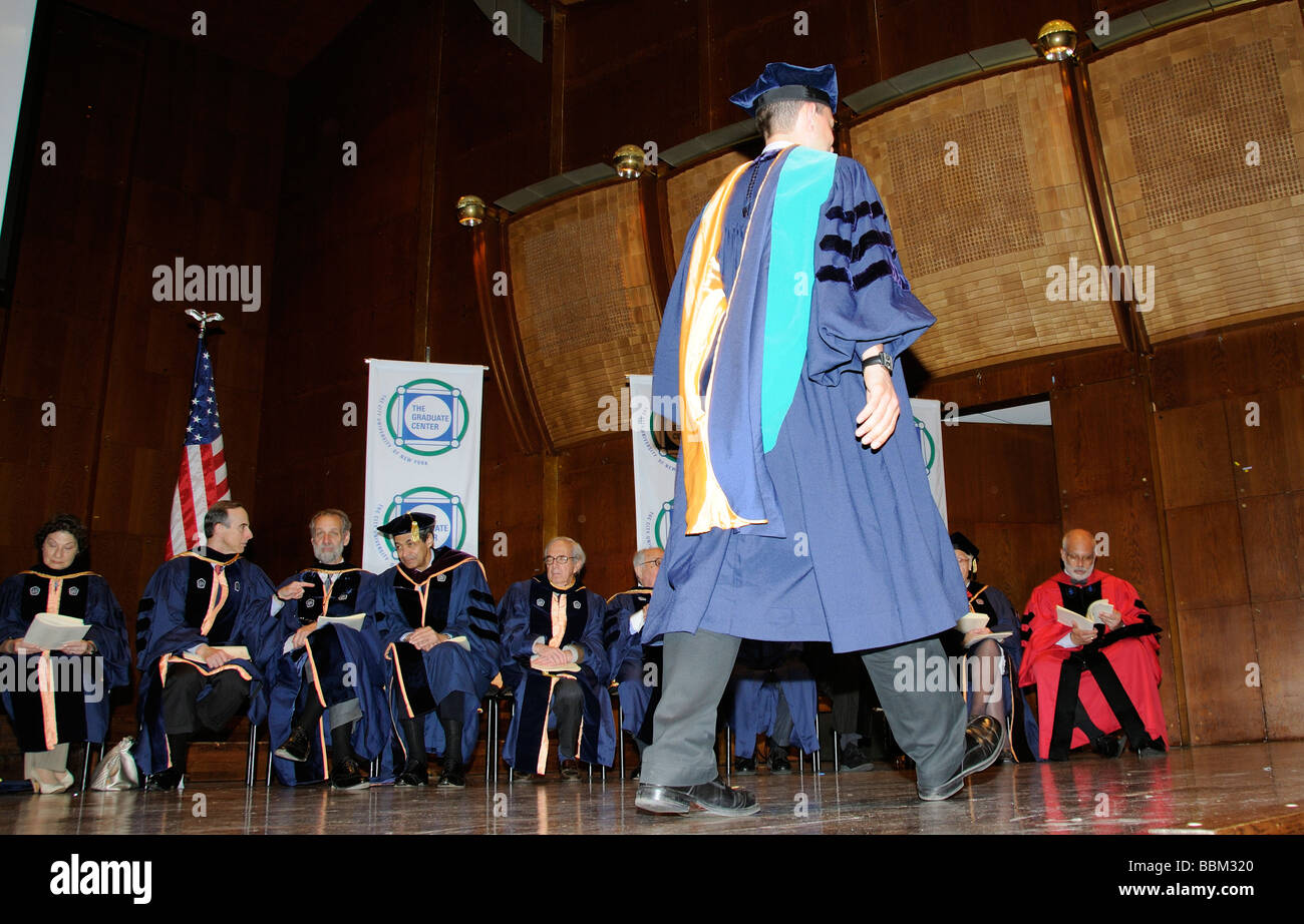 Graduierung Zeremonie männlicher Absolvent tragen Mütze und Mantel mit Universität Beamten entlang der Bühne Stockfoto