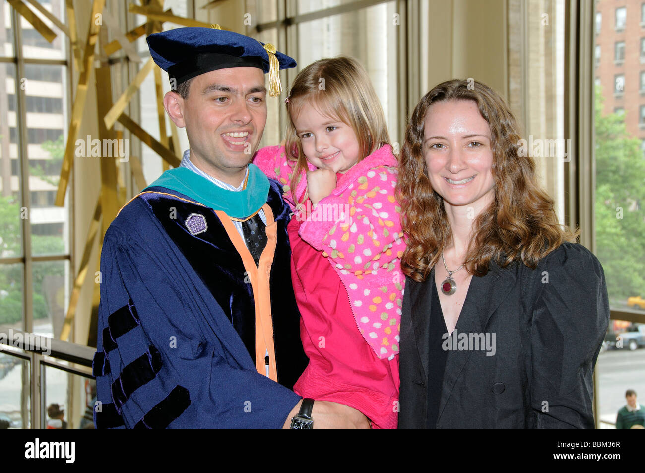 Graduierung Zeremonie Porträt der Absolvent tragen Mütze und Mantel Celebtrating mit seiner Frau und Tochter Stockfoto