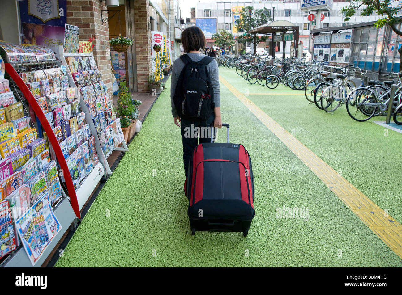 Junge Frau Reisenden zieht Koffer in Richtung Bahnhof Oita, Oita, Japan Stockfoto