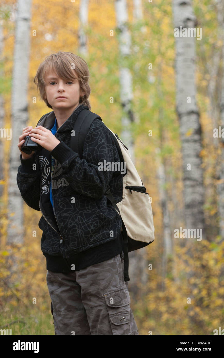 Zehn Jahre alter Junge mit Fernglas tragen Hanf Rucksack, See Katherine Riding Mountain National Park, Manitoba Stockfoto