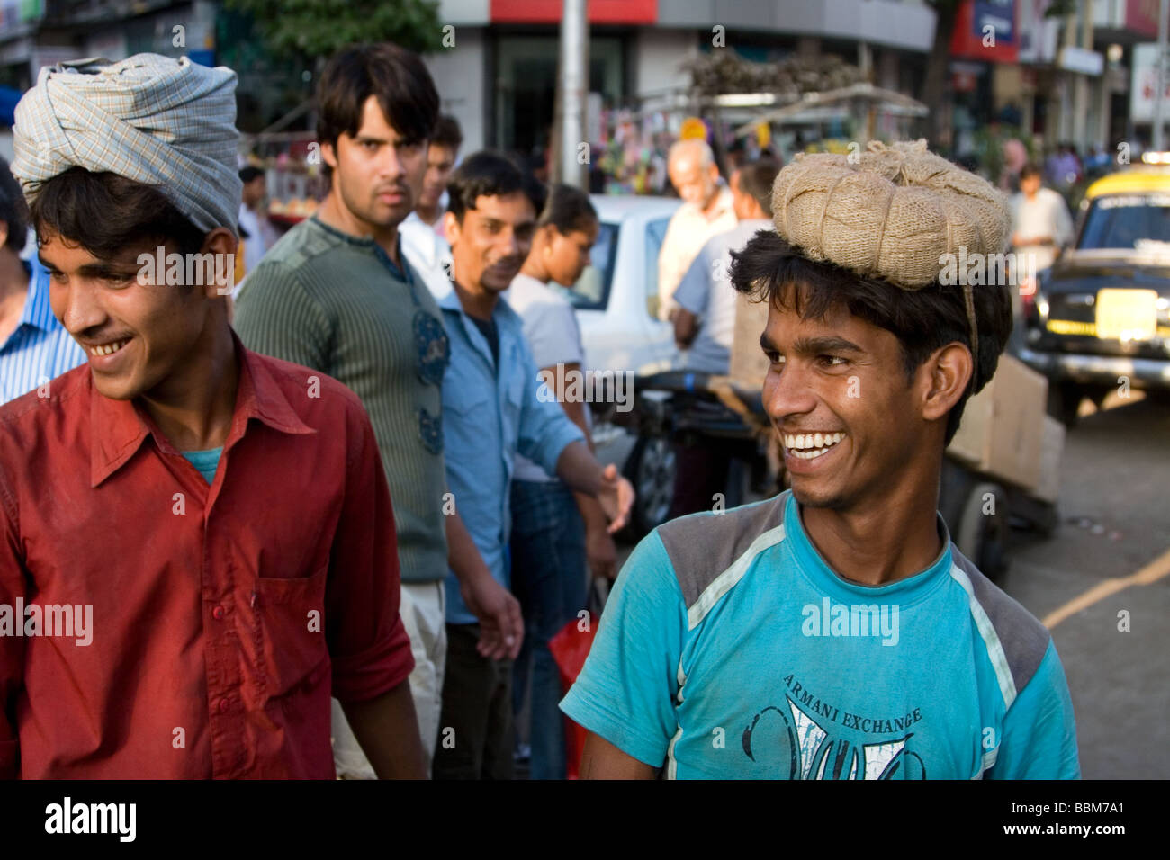 2 indische Kulis Lachen außen Crawford Market, Mumbai, Indien. "Coolie" ist ein Arbeiter, der schwere Lasten trägt. Stockfoto