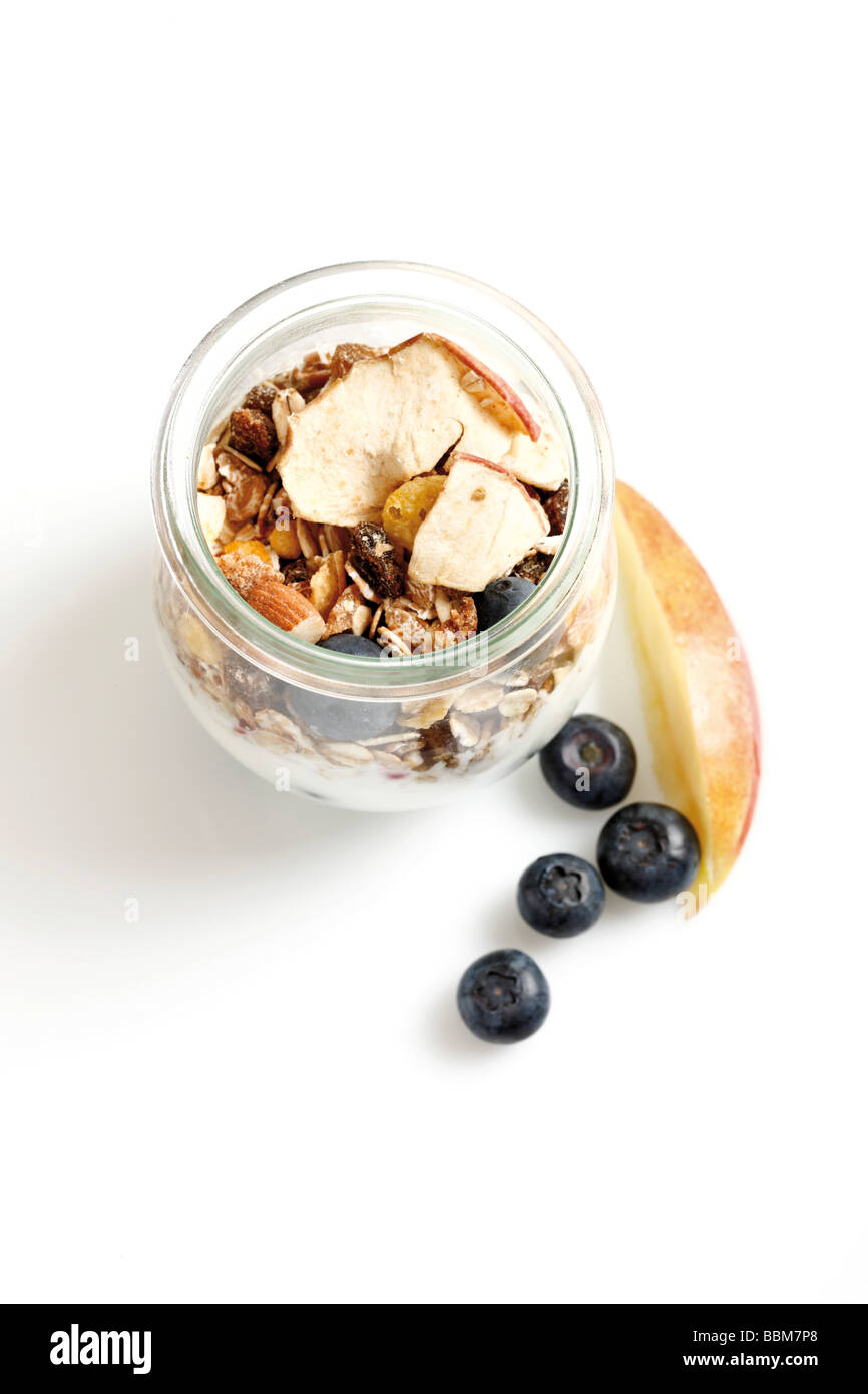 Müsli mit Joghurt in ein kleines Glas, Löffel Joghurt, Heidelbeeren, getrocknete Früchte, Apfel Stockfoto