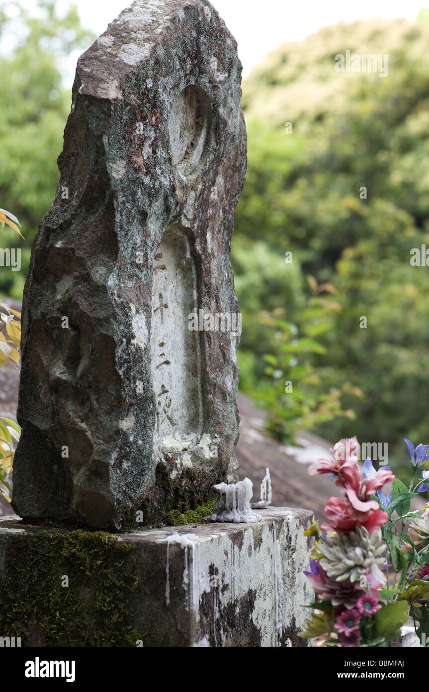 Ein buddhistischer Grabstein Denkmal markiert mit dem Tod der Person und eine Kerze brannte teilweise vor Stockfoto