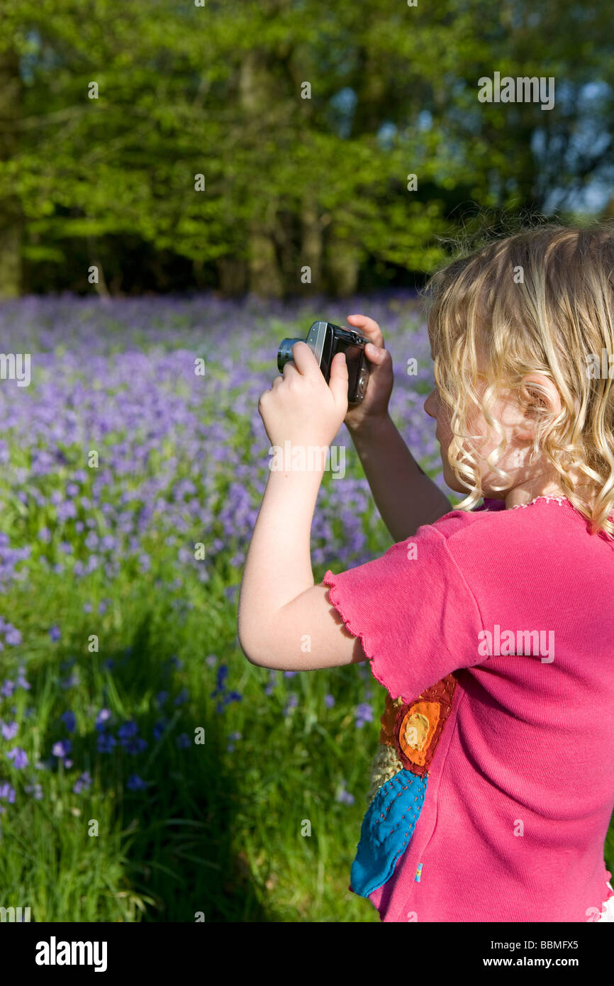 England, West Dorset, Thorncombe. Sping im Wald spielt ein junges Mädchen mit einer digitalen Kamera. (MR) Stockfoto