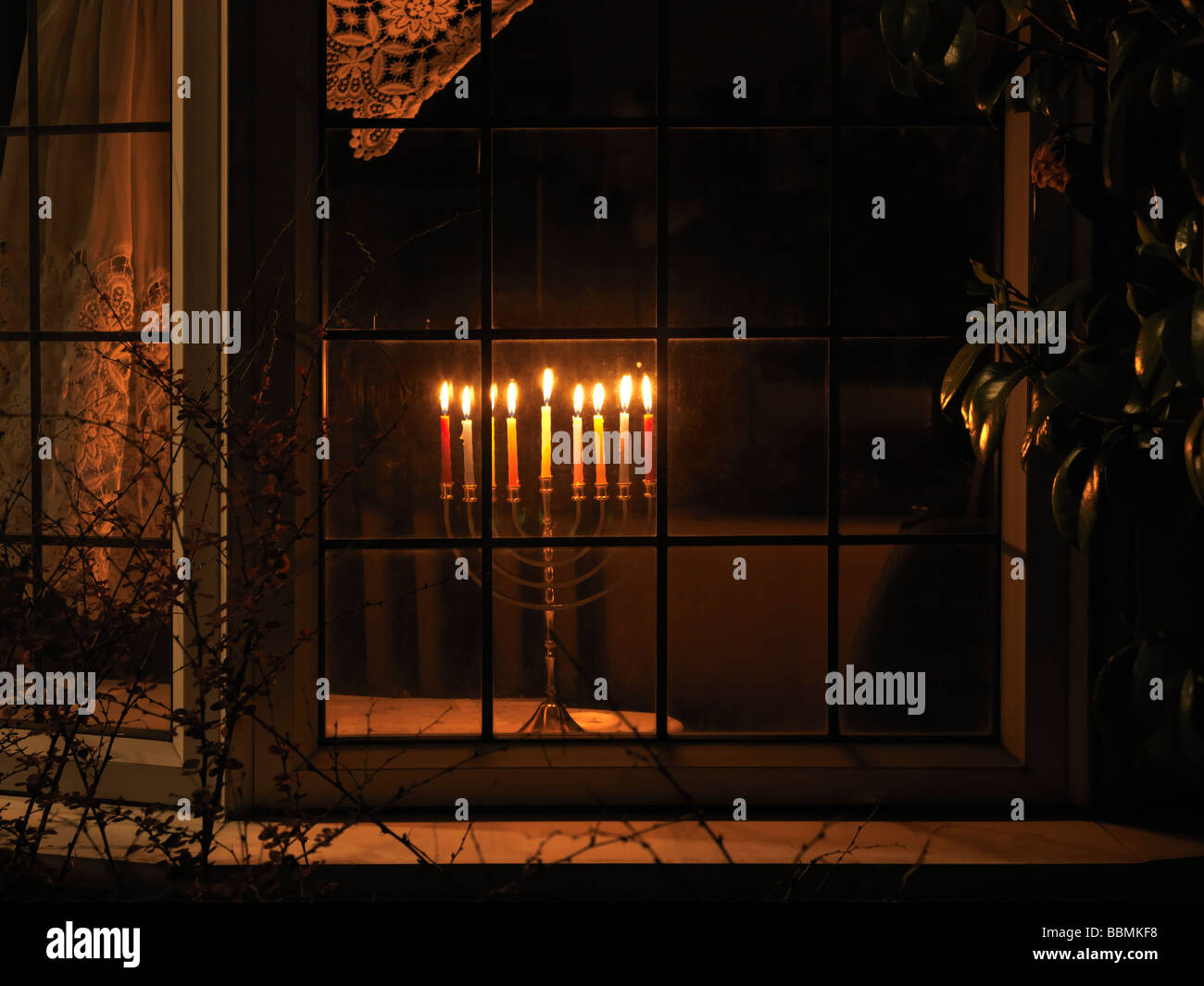 Menorah beleuchtet in einem Fenster für Hanukkah das jüdische Lichterfest Stockfoto