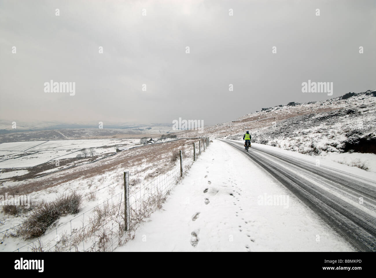 Einsame männliche Radfahrer auf einer entfernten eisigen Schnee bedeckt Straße Stockfoto