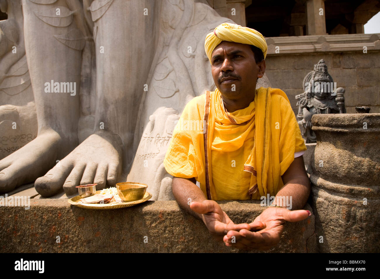 Ein Priester steht am Fuße der Statue von Lord Bahubali bei Shravanabelagola, Karnataka, Indien. Stockfoto