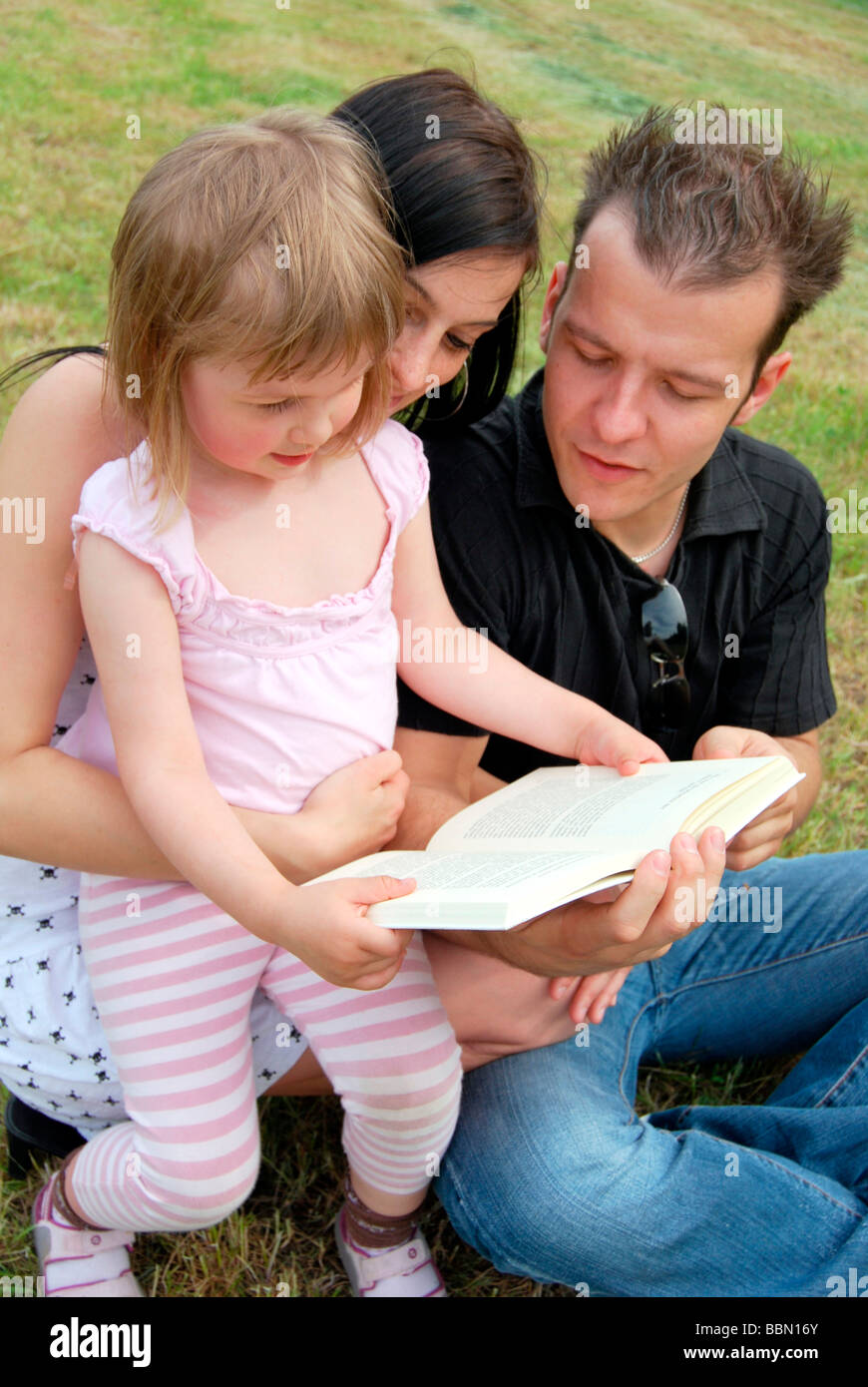 Familienglück, Mutter, Vater und Kind gemeinsam ein Buch zu lesen Stockfoto