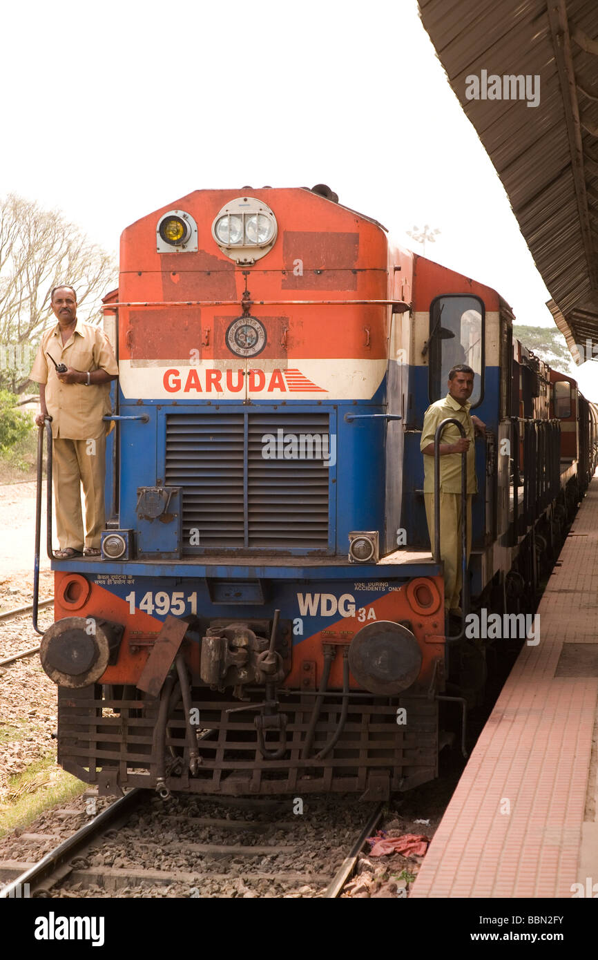 Eine indische Dieselmotor läuft durch einen Bahnhof in Indien. Die Ingenieure stehen auf der Fußplatte. Stockfoto